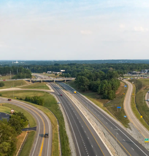 A highway intersection with multiple lanes and trees around.