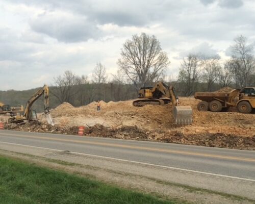 Construction vehicles working on a site with a backhoe digging in the background.