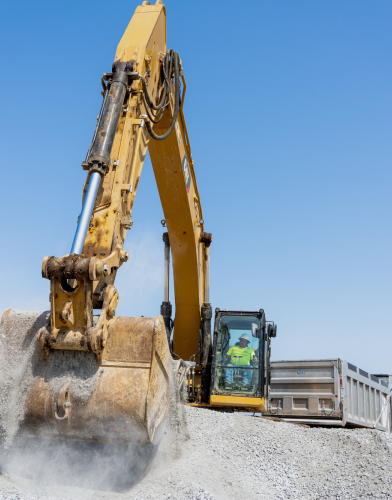 Close up of Excavator moving rocks with excavator operator visible in the background