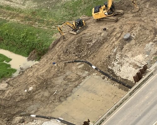 Aerial view of an excavation site with heavy equipment and dirt piles.